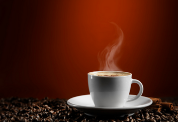 Image shows a cup of coffee on coffee beans against a shaded red background