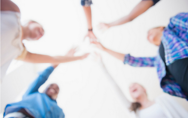 Image shows an out-of-focus group of people putting their hands together